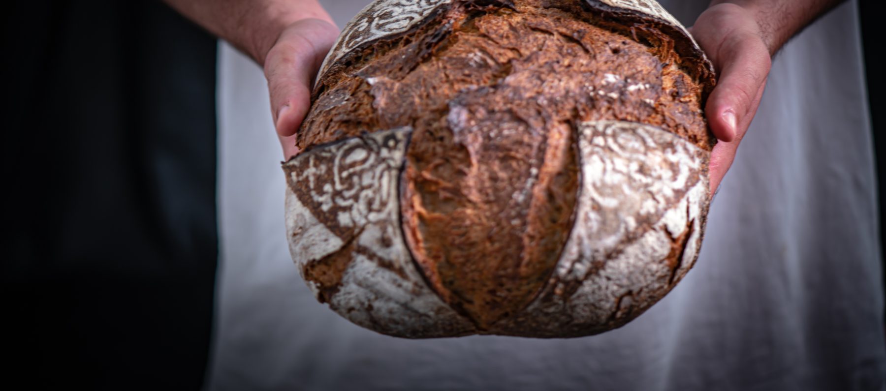 Un pain au levain tout juste sorti du four, tenu à deux mains